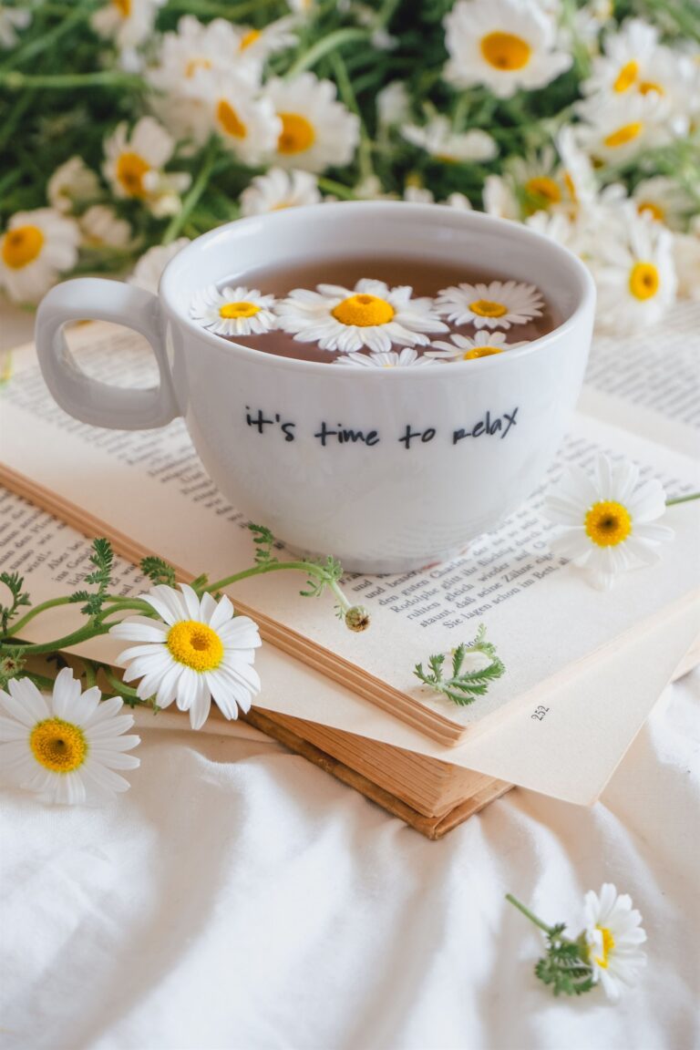 Chamomile tea cup that reads 'it's time to relax' surrounded by daisies