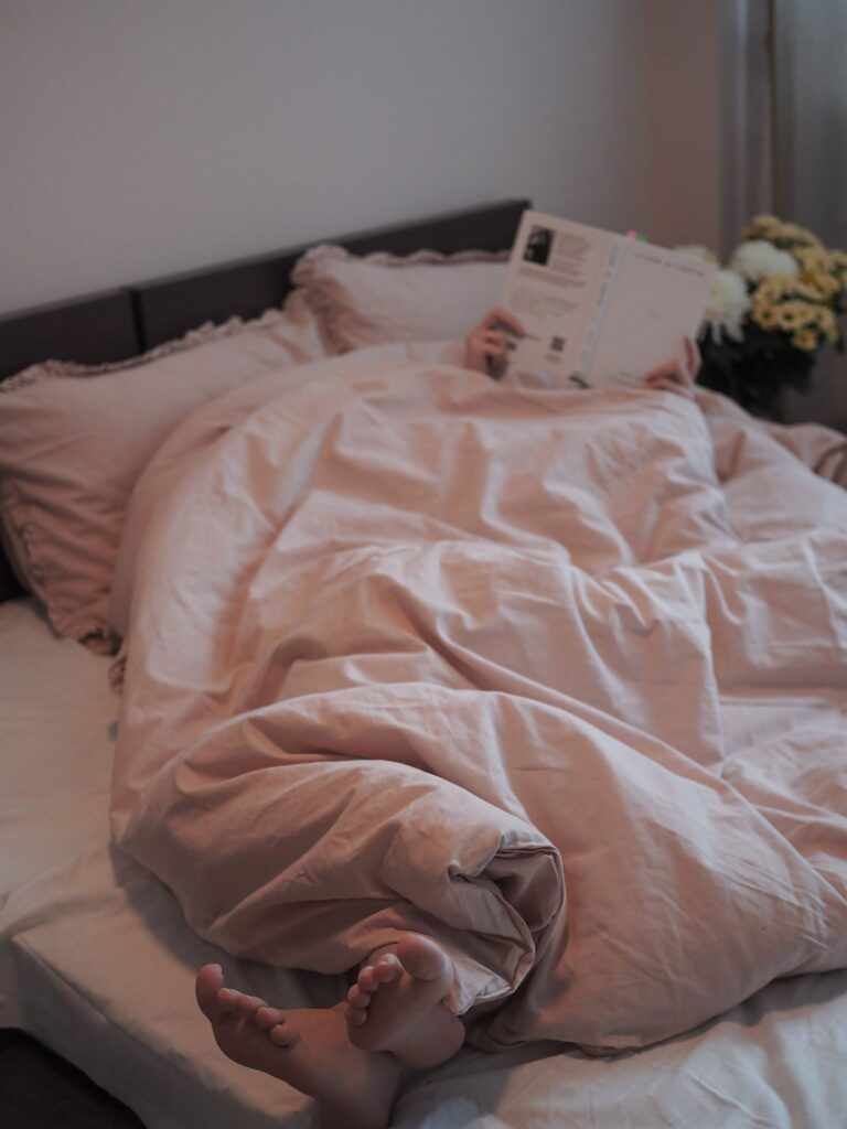 Cozy feet peeking out from a blanket while reading in bed