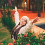 Woman smiling with arms raised joyfully in a garden