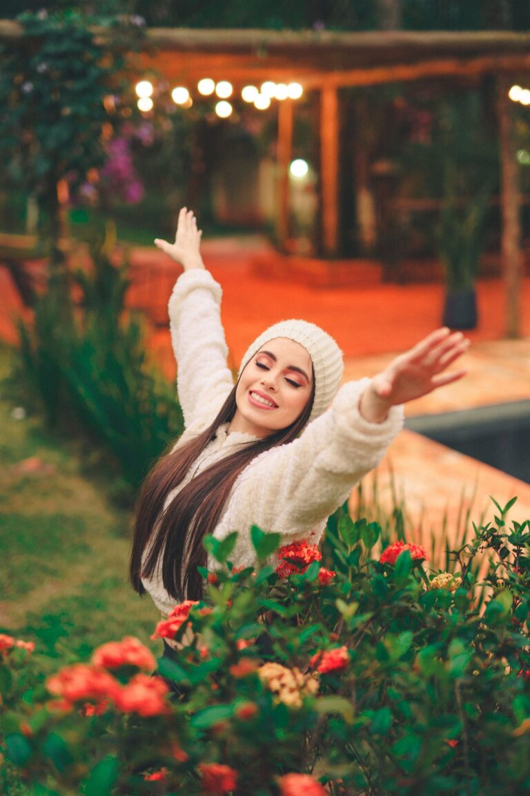Woman smiling with arms raised joyfully in a garden
