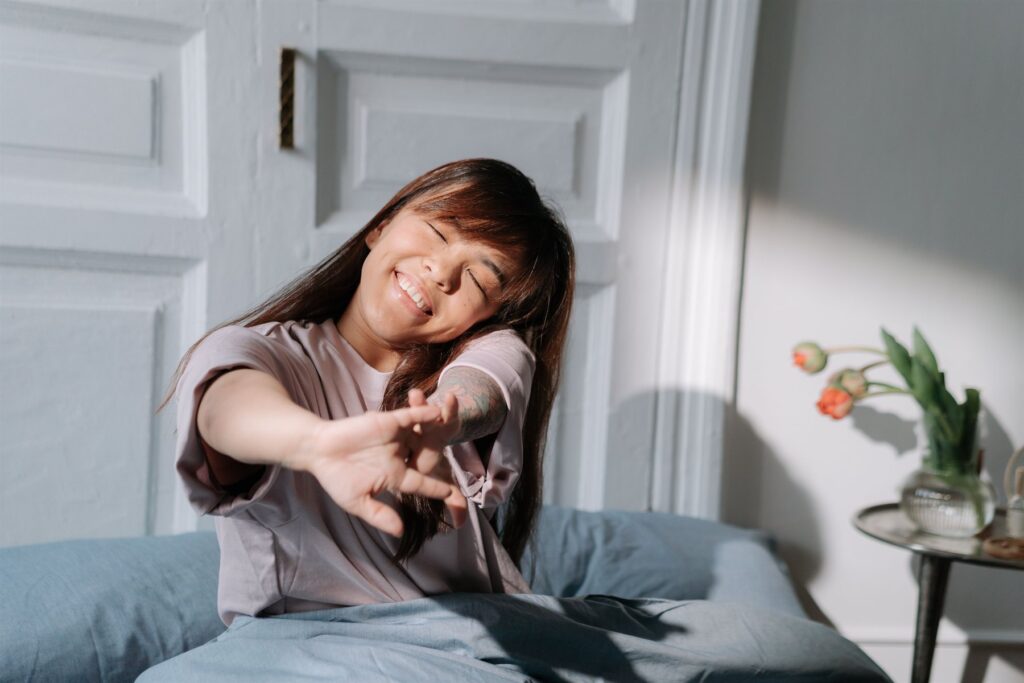 Woman stretching happily as she wakes up, tulips on the nightstand
