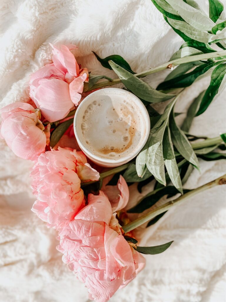 Pink peonies beside a warm cup of coffee, a soft flatlay