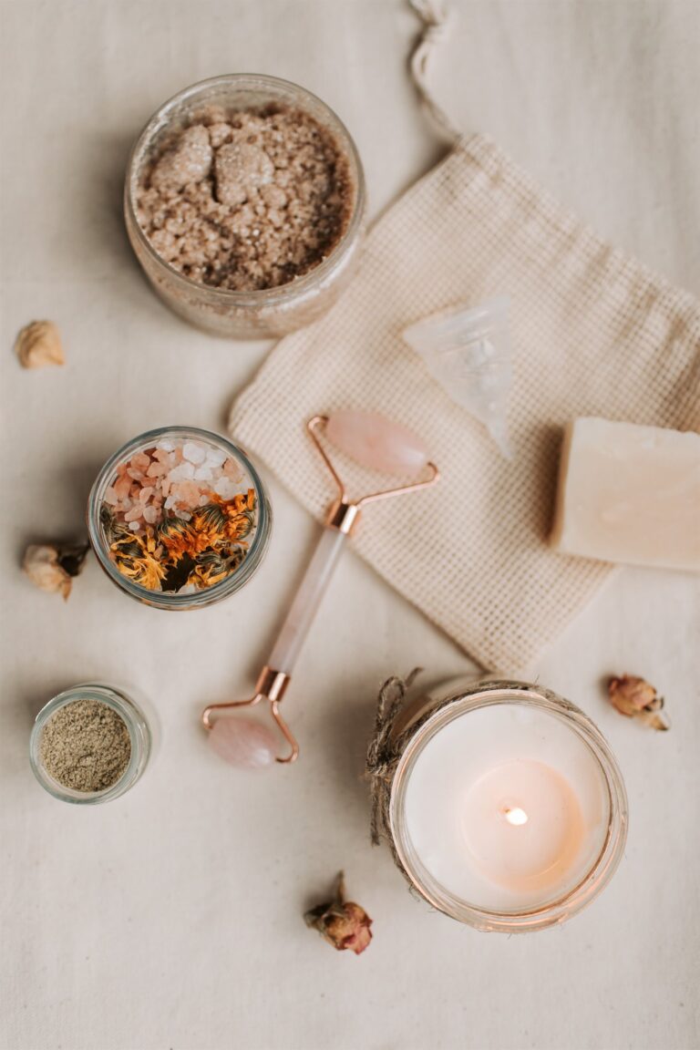 Bath salts, jade roller, soap and a lit candle laid out as a self-care ritual