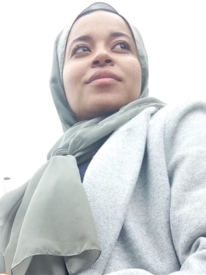 Adhra, founder of Her Soft Glow, in a sage green headscarf and soft grey coat